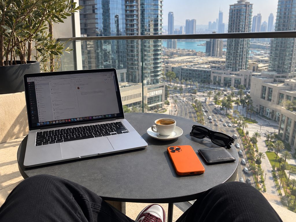 Portátil, móvil y café en una terraza con vistas a la ciudad